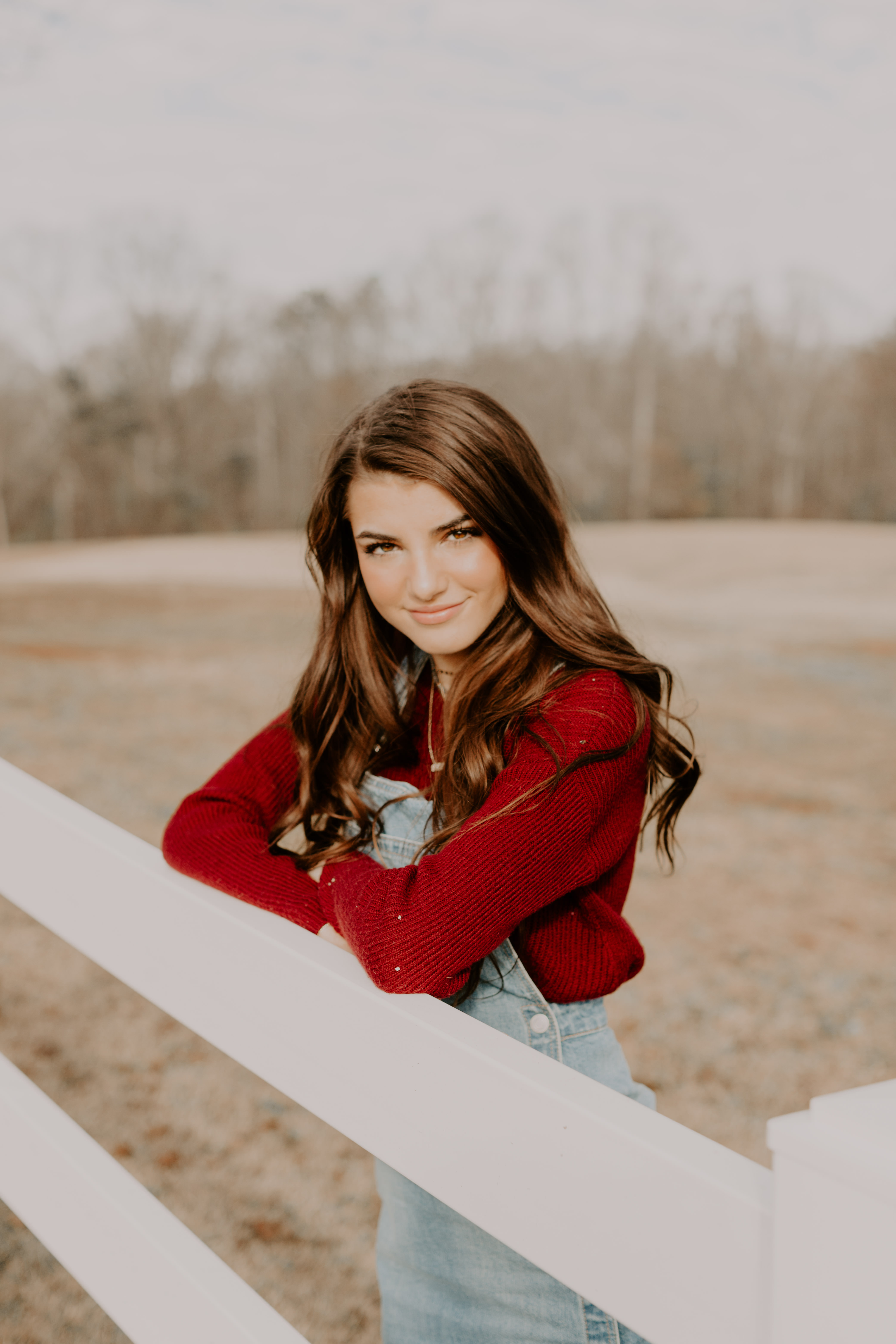 Meghan H. fence red longsleeve overalls open field pose inspiration model senior pictures Atlanta photographer smiling white house leaning Olie West bench